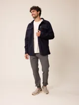 Sobrecamisa de polar azul marino con cierre frontal de botones a presión. Presenta bolsillos frontales con solapa, uno de ellos con cierre de cremallera adicional y detalles en contraste de material técnico.