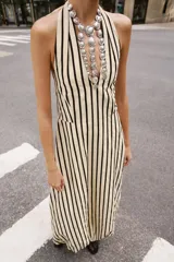 Vestido midi de cuello halter anudado, escote en pico y espalda descubierta, con diseño a rayas verticales y bajo abullonado con elástico interior.