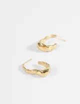 Aros tipo argolla de acero quirúrgico con diseño de superficie irregular y acabado brillante.