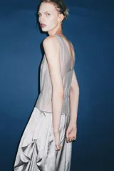 Vestido largo de tirantes con escote redondo, confeccionado en mezcla de viscosa. Presenta un diseño combinado con la parte superior en tejido ligero semitransparente y la parte inferior con volumen y drapeado asimétrico.