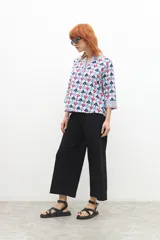 Blusa de manga larga con cuello camisero y estampado con motivos geométricos en tonos azul, rojo y blanco.