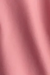 Malla enteriza de un hombro color rosado, con ribetes festoneados en el escote asimétrico y bretel, y piernas de corte alto.