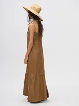 Vestido midi de denim color marrón, con corte holgado, breteles finos con lazos ajustables y detalle de volado en el ruedo.