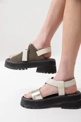 Sandalias de cuero color marrón con tiras cruzadas en blanco y negro, suela track y ajuste con velcro.