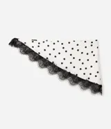 Pañuelo triangular de poliéster con acabado satinado, color blanco con estampado de lunares negros y detalle de encaje negro aplicado en uno de sus bordes.