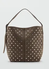 Bolso tipo hobo de gamuza marrón, adornado con tachas metálicas plateadas distribuidas por toda la superficie. Cuenta con una correa ajustable y cierre superior.