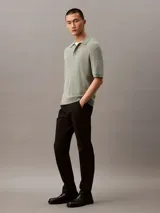 Pantalón chino de corte slim confeccionado en tejido elástico de algodón orgánico. Presenta cierre de botón y cremallera, bolsillos laterales y bolsillos traseros ribeteados.