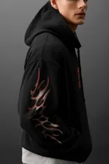 Buzo hoodie negro oversize con estampado rojo en el pecho y diseño tribal en las mangas.