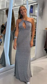 Vestido largo plateado de fiesta con acabado brillante, escote halter cruzado con abertura tipo lágrima y diseño al cuerpo con caída fluida.