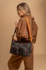 Bandolera de tafeta impermeable color beige, con dos bolsillos frontales con cierre y correa regulable. Diseño práctico y liviano ideal para uso diario.