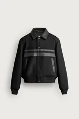 Cazadora cropped fit de color negro para hombre, con cuello solapa y detalles combinados en tejido efecto piel. Presenta mangas largas, bolsillos de doble vivo en la cadera, cierre frontal con botones a presión y puños y cintura elásticos ribeteados.