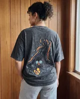Remera de algodón con efecto stone wash en color negro, de corte oversize y manga corta. Presenta un estampado artístico en la espalda con motivos de figuras estilizadas y hongos en tonos vibrantes.