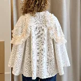 Ruana tejida de color blanco, confeccionada con lanas, con detalles de volados en gasa transparente a lo largo de los hombros y mangas, adornados con cuentas tipo perlas.