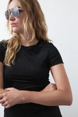 Top de manga corta color negro, confeccionado en terciopelo con textura acanalada y leve brillo. Tiene un calce ajustado y cuello redondo.