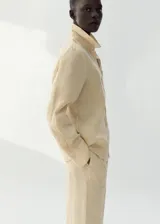 Pantalón de lino color beige, de diseño recto y largo con tiro medio, dos bolsillos laterales y cintura ajustable.