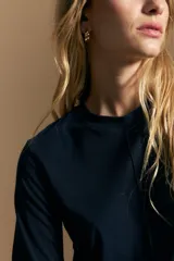 Remera de manga larga en color negro, con cuello redondo y costura vertical central en el frente. Presenta un diseño minimalista de calce ajustado y líneas limpias.