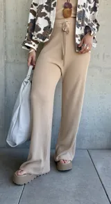 Pantalón de punto color beige, de corte ancho y tiro alto, con cintura elástica y cordón ajustable.