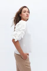 Remera color beige con mangas cortas y volados con borde naranja.