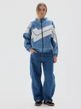 Campera de jean con diseño de paneles en denim azul y blanco, con cierre frontal completo, cuello alto, puños y cintura elásticos.