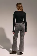 Sweater de punto acanalado en color negro, con cuello redondo y mangas largas. Presenta detalles de tachas metálicas plateadas dispuestas en líneas verticales a los costados del torso.