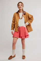Minifalda color coral, de tela liviana con dos capas de volados, cintura elastizada con cordón ajustable y borde festoneado con puntilla.