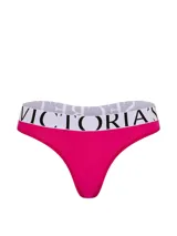 Tanga de microfibra fucsia de tiro bajo, con cintura elástica ancha en color blanco con el logotipo de la marca impreso en negro.