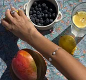 Pulsera rígida abierta de plata con bolitas texturadas en los extremos.