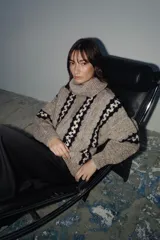 Sweater de punto grueso con cuello tortuga, diseño de rayas verticales con patrón geométrico en contraste, manga larga y corte holgado.