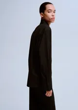 Camisa negra de manga larga con cuello clásico y cierre frontal abotonado.