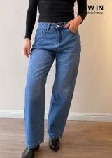 Pantalón de jean corte mom fit con tiro alto, confeccionado en denim de lavado clásico. Presenta cierre frontal con botón y cierre metálico, con bolsillos funcionales delanteros y traseros.