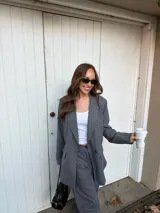 Conjunto de blazer y pantalón de lino gris con diseño de rayas diplomáticas. El blazer es de corte amplio con doble botonadura, y el pantalón es de corte recto y tiro alto.
