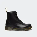 Botas Dr. Martens modelo 1460 de 8 ojales, confeccionadas en cuero liso negro. Presentan la icónica costura amarilla en el borde de la suela, suela acanalada con amortiguación de aire y tirador en el talón con inscripción.