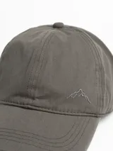 Gorro con visera color beige, con logo bordado de una montaña en el frente.