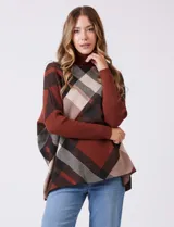 Polera estilo poncho de corte oversize, con cuello alto tejido y mangas largas con puños elásticos. Presenta un diseño de estampado a cuadros en tonos bordó, beige y negro.