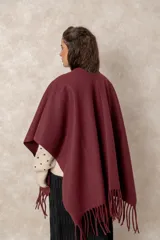 Ruana abierta de color beige, confeccionada en tejido de punto con terminación de flecos en el ruedo.