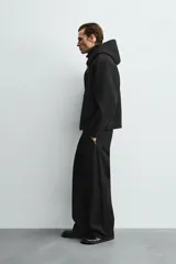 Sudadera con capucha de corte relajado confeccionada en tejido técnico con elasticidad y acabado efecto neopreno. Presenta cierre frontal de cremallera de doble dirección, bolsillos tipo canguro y terminaciones en rib.