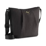 Bolso tipo bucket de la marca Puma, color negro con textura arrugada y logo metálico dorado en la parte frontal. Cuenta con correa ajustable para el hombro y cierre superior.