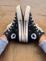 Zapatillas de lona color beige, tipo bota, con cordones marrones, puntera de goma y logo de peach engomado.