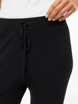Pantalón tejido de punto con tiro medio y corte holgado. Presenta cintura elastizada con cordón ajustable y textura acanalada fina, ofreciendo una caída fluida y cómoda.