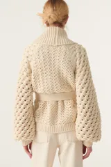 Cárdigan color crema de tejido calado con mangas abullonadas y cinturón para atar.