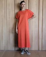 Vestido midi color naranja, de corte recto y holgado, con cuello redondo y mangas cortas. Presenta costuras decorativas en blanco en los bordes.