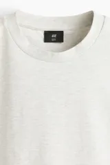 Remera de corte holgado confeccionada en punto interlock de algodón, con cuello redondo acanalado y hombros caídos.