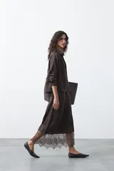 Falda midi negra de caída fluida con cintura elastizada y un amplio detalle de encaje negro en el bajo.