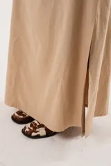 Falda larga color beige confeccionada en tela suave con acabado tipo piel de durazno y cierre invisible lateral.