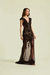 Vestido largo negro con escote en V, mangas cortas estilo cap y aplicaciones de encaje floral y bordados con pedrería sobre base de tul transparente.