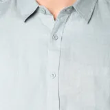 Camisa de lino color gris topo, de corte clásico, con cuello abotonado, manga larga y bolsillo en el pecho.