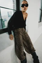 Pantalón bombacho de tiro medio con estampado animal print, bolsillos delanteros, bajo con puño y cierre frontal con cremallera y gancho metálico.