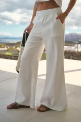 Pantalón de lino color blanco, de tiro alto y corte oxford con perneras amplias. Cuenta con cintura elastizada y bolsillos laterales.