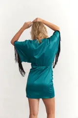 Vestido corto celeste de satén con escote en V, mangas cortas con flecos negros y drapeado en la falda.