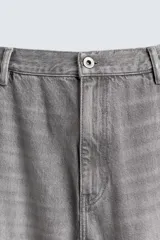 Pantalón de jean estilo carpintero con corte relaxed fit, tiro medio y pierna recta. Presenta un lavado azul medio con efecto desgastado y roturas en las rodillas. Incluye bolsillos laterales tipo plastrón, tira multifunción en la pierna, cierre frontal con cremallera y botón.